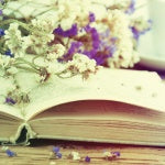 A purple and white dandelion on top of an open book. Global Healing's List of Top 50 health and Nutrition Quotes.