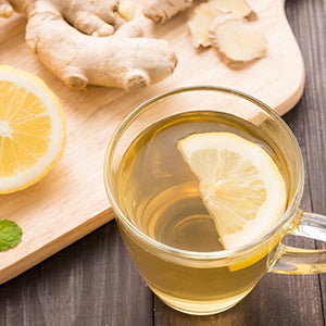 Tea with lemon in a glass cup over a wooden background with of natural ingredients.