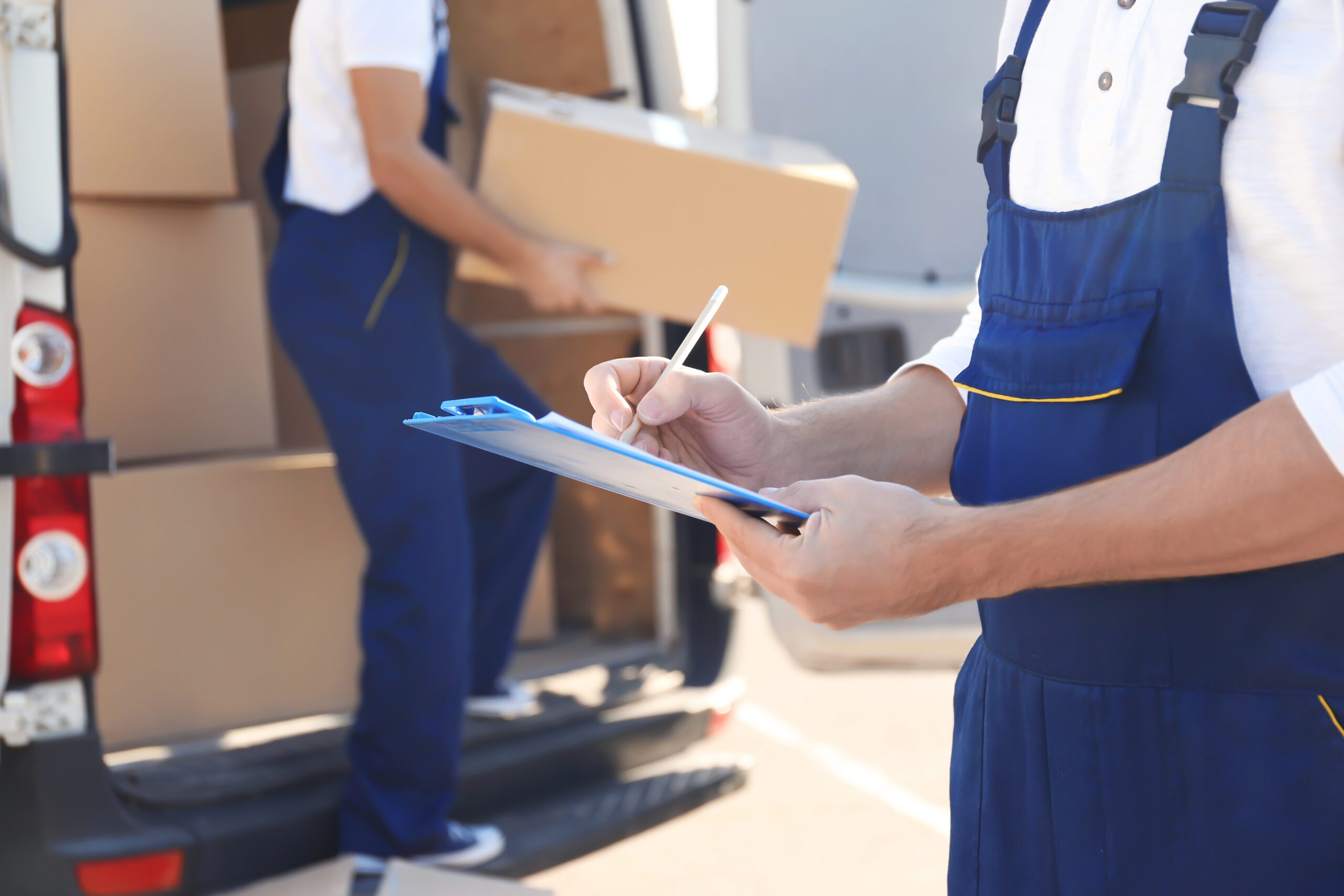 delivery man checking list on clipboard near car