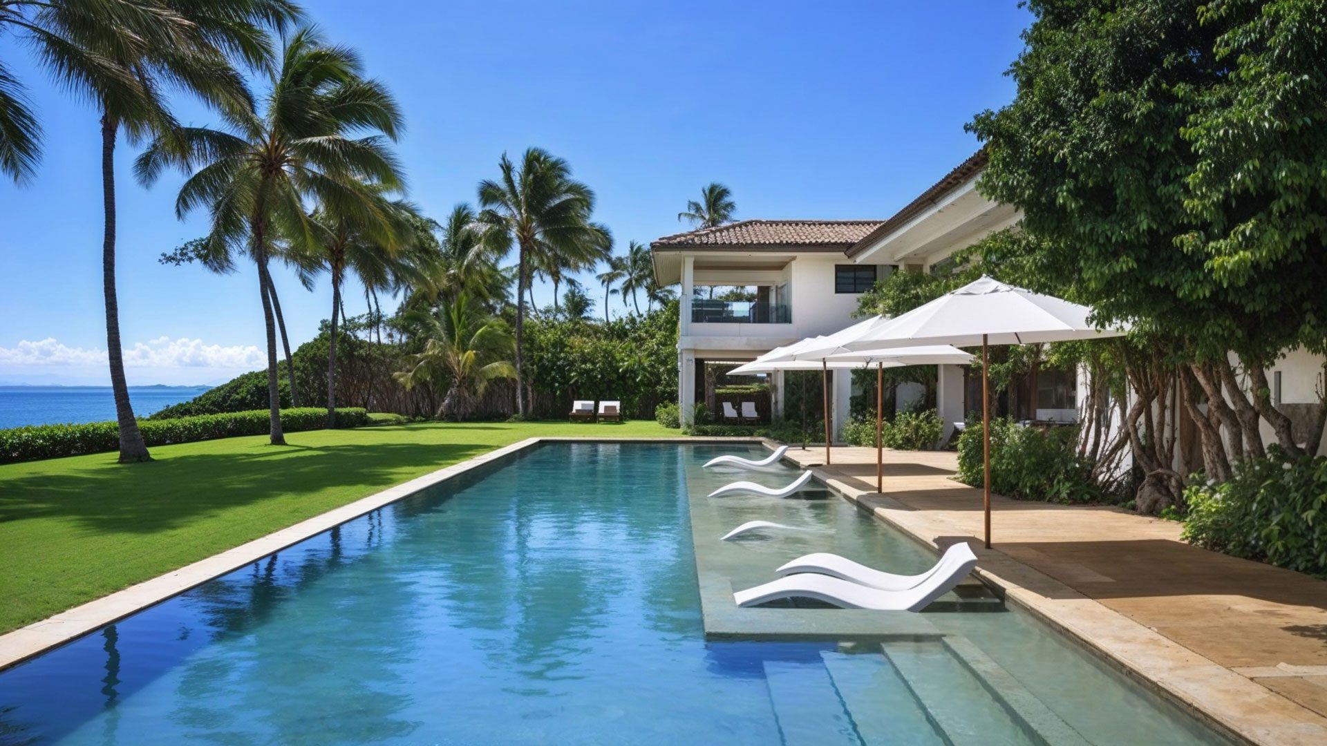 Resort Style Lap Pool With Sun Shelf Loungers And Ocean Backdrop